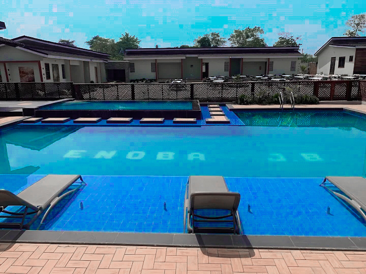 Large outdoor swimming pool with loungers beside the venue buildings