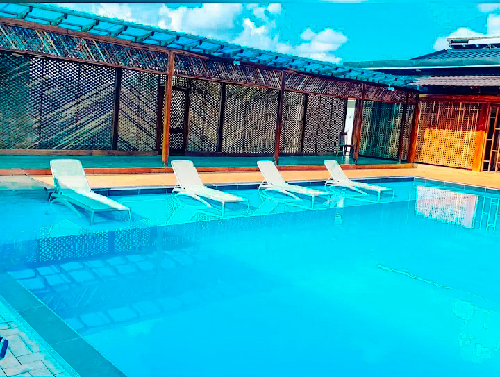 Poolside sun loungers under a wooden shaded walkway